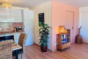 A modern kitchen with a dining area, a potted plant, a bookshelf, and a wooden cabinet. - A Cottage Amid the Birdsong. Beautiful views and tranquility, 300 meters from Flow Vélo (Chazelles)