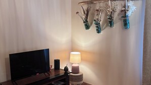 Ett vardagsrum med en platt-TV, en lampa och ett soffbord.