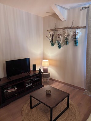 A living room with a flat-screen TV, a lamp, and a coffee table. - A Cottage Amid the Birdsong. Beautiful views and tranquility, 300 meters from Flow Vélo (Chazelles)