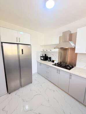 A modern kitchen with a stainless steel refrigerator, a gas stove, and marble flooring. - NEW Pool Villa, 3 Min to Downtown, Sleeps 8 (Punta Cana)