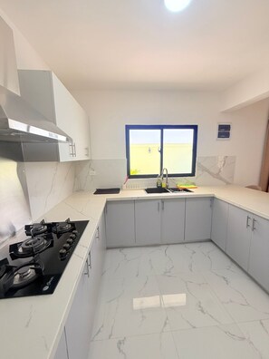 A kitchen with a gas stove, cabinets, a window, and a view of the outside. - NEW Pool Villa, 3 Min to Downtown, Sleeps 8 (Punta Cana)