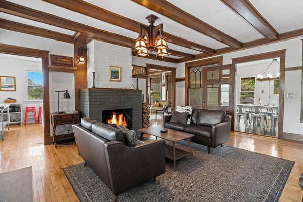 A spacious living room with a fireplace, leather sofas, and a dining area with a view. - Belclare - Vineyard Estate (Northport)