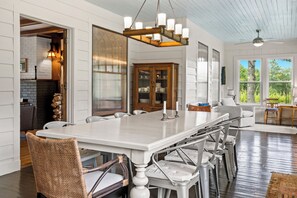 A spacious dining area with a large table, multiple chairs, and a hanging light fixture. - Belclare - Vineyard Estate (Northport)