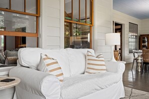 A modern living room with a white sofa, striped pillows, a round side table, and a lamp. - Belclare - Vineyard Estate (Northport)