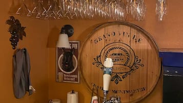 A bar area with a wooden wall, a beer tap, and a wine glass rack.