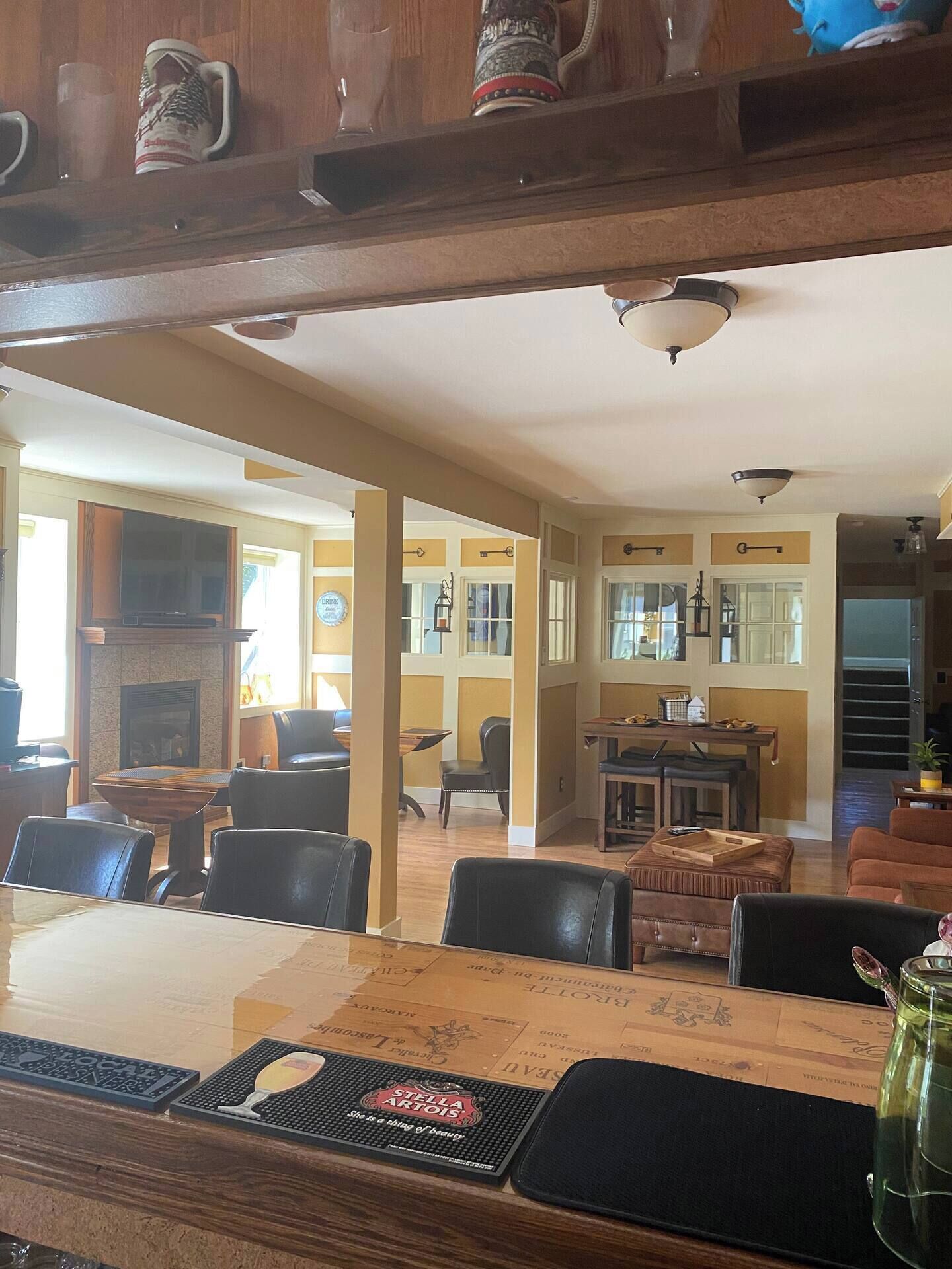 A dining area with a wooden table, chairs, and a fireplace. There are multiple windows and a ceiling fan.