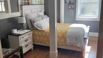 A bedroom with a bed, bedside table, lamp, and a window with curtains.