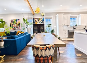 Eine moderne Küche mit weißen Schränken, ein Essbereich mit einer blauen Couch und einem großen Holztisch.