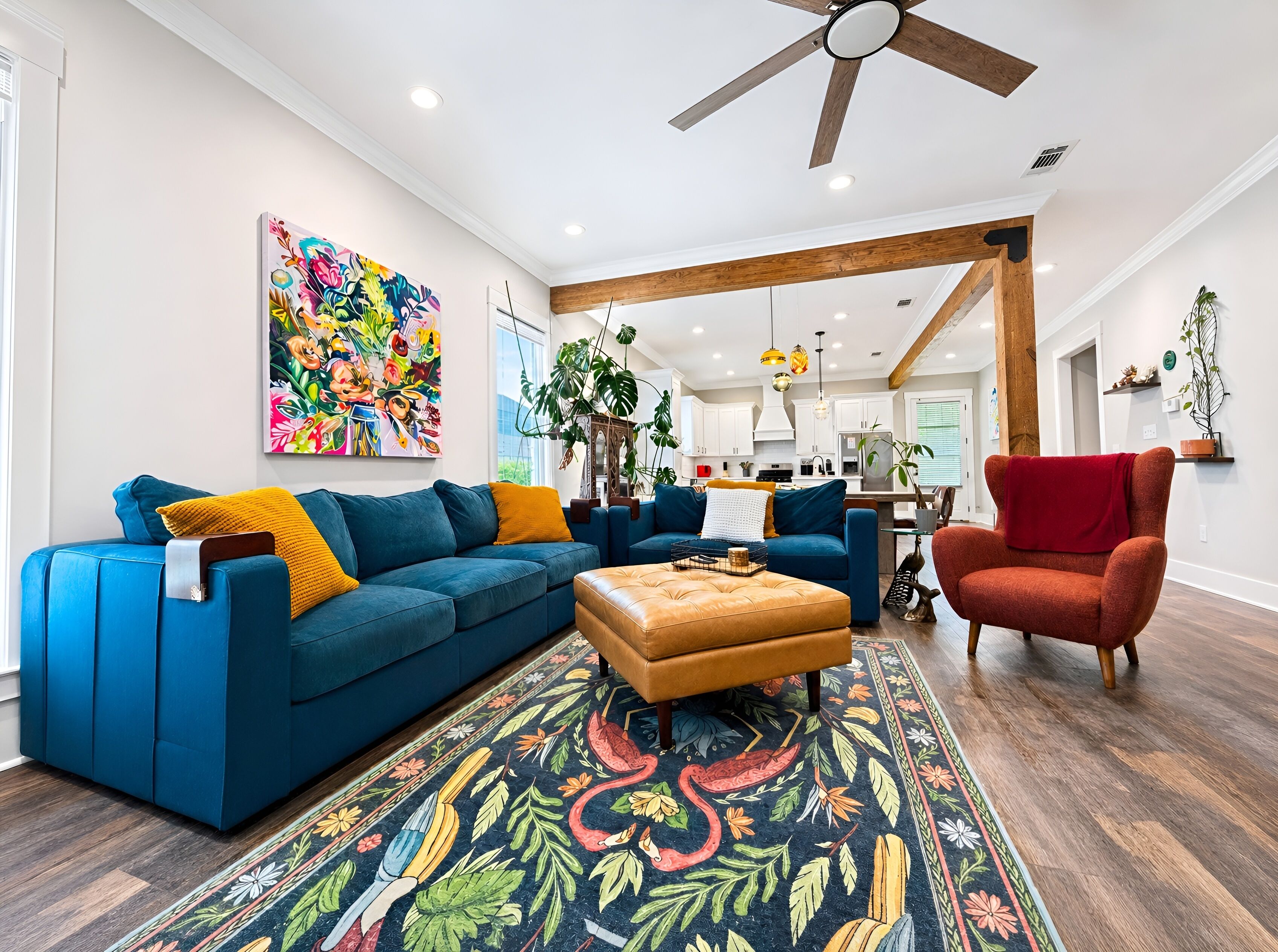 Uma sala de estar com um sofá azul, uma poltrona vermelha e um tapete colorido.