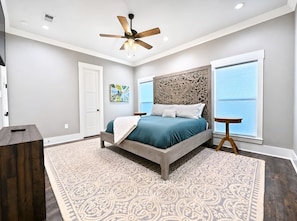 A bedroom with a bed, a ceiling fan, a window with blinds, and a patterned rug. - The Seaglass Bungalow - Where Colorful Comfort Meets Gulf Coast Charm (Gulfport)