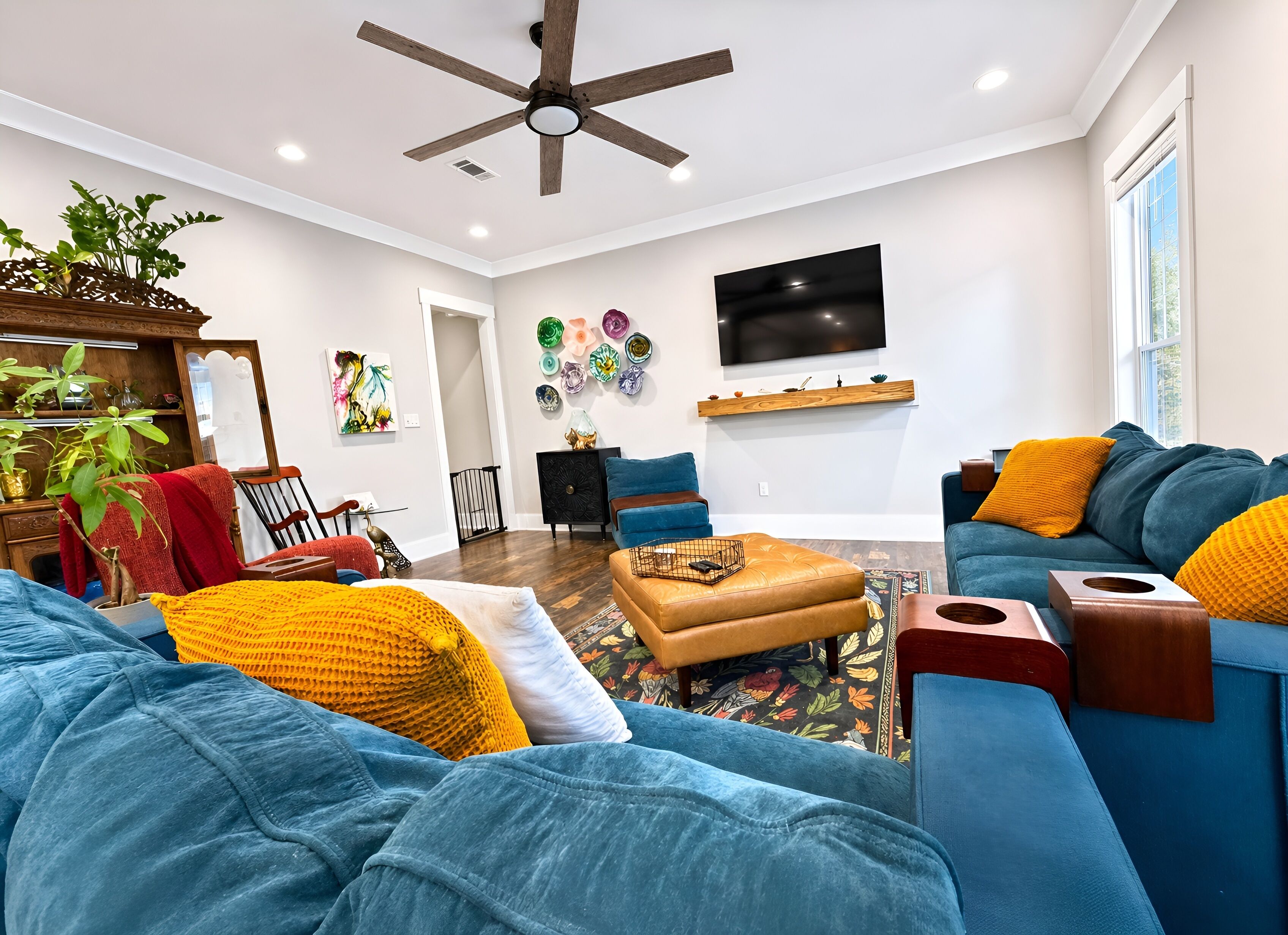 A modern living room with a ceiling fan, a flat-screen TV, a sofa set, and a coffee table.