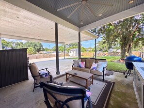 An outdoor patio with a covered seating area, a grill, and a view of the neighborhood. - The Seaglass Bungalow - Where Colorful Comfort Meets Gulf Coast Charm (Gulfport)
