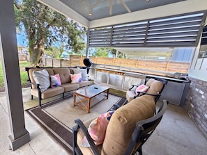 Eine Außenpatio mit eingebautem Grill, einer Sitzgelegenheit und Blick auf den Garten.