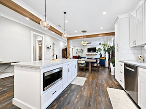 A modern kitchen with a central island, white cabinetry, and a wooden ceiling. - The Seaglass Bungalow - Where Colorful Comfort Meets Gulf Coast Charm (Gulfport)
