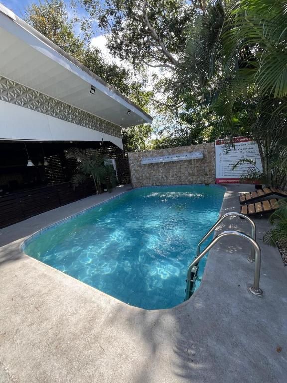 A swimming pool with a concrete deck, surrounded by a stone wall and greenery.