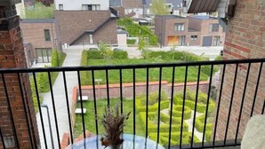 A balcony with a round glass table, two chairs, and a vase with dried flowers. - Villa Clementine (Kruishoutem)