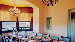 A dining area with a long table set for a meal, surrounded by chairs, with a chandelier above. - Villa Clementine (Kruishoutem)