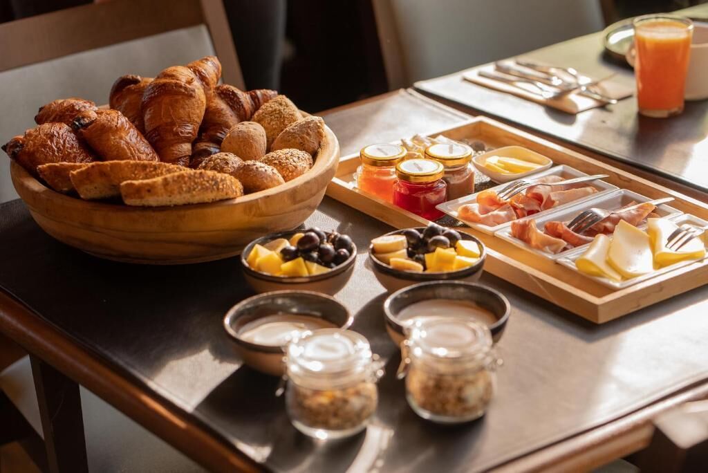 A breakfast buffet with pastries, fruits, cheeses, meats, and condiments.