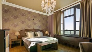 A bedroom with a bed, nightstand, lamp, and a large window with curtains. - Villa Clementine (Kruishoutem)