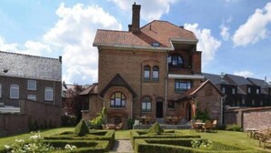 A large brick building with a symmetrical garden featuring circular hedges and a gravel path. - Villa Clementine (Kruishoutem)