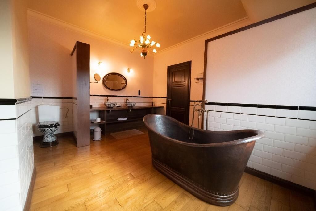Un baño con una bañera independiente, inodoro, lavabo y espejo.