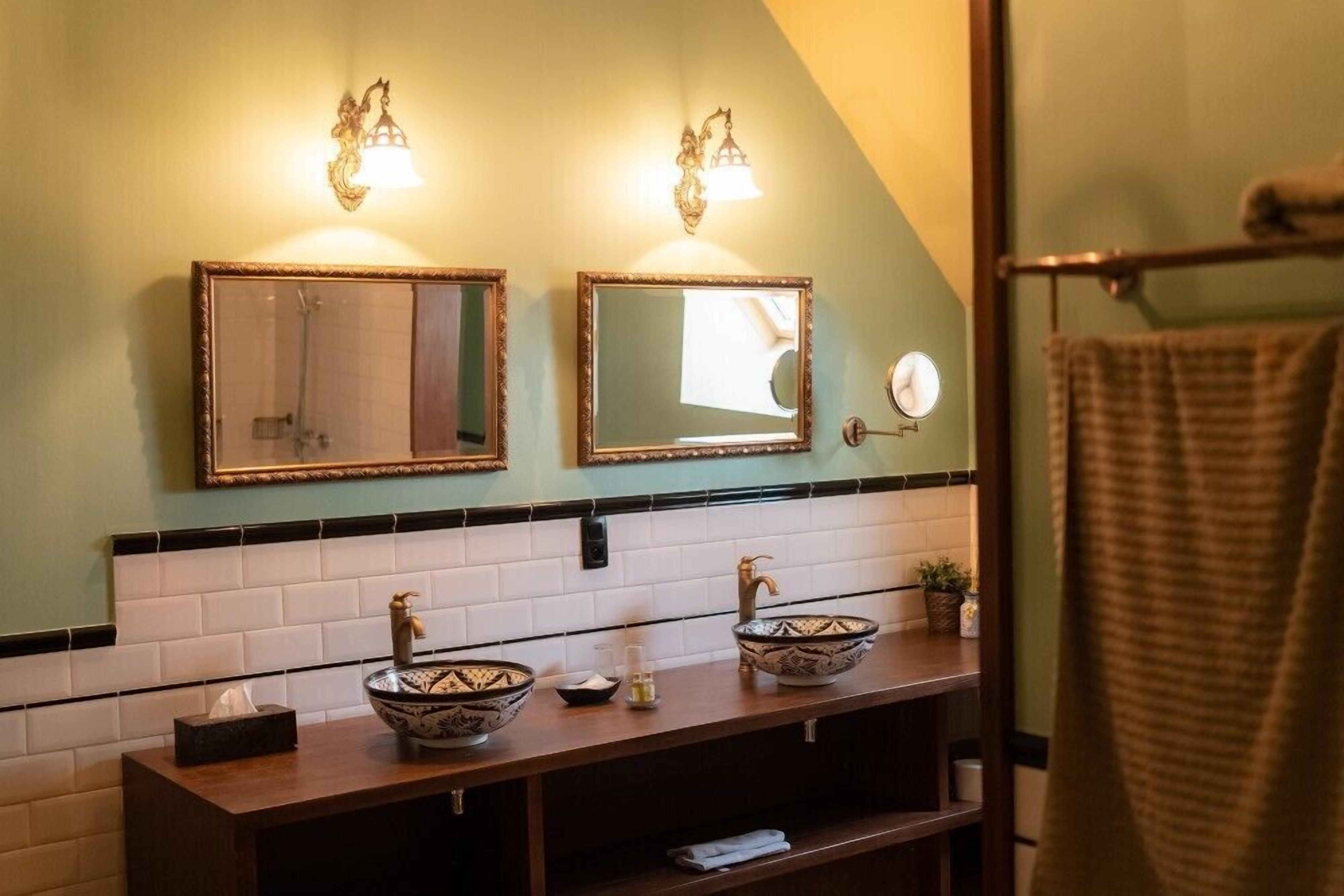 Casa de banho com duas pias, um porta-toalhas e um espelho.