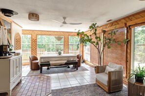 A spacious room with a dining table, chairs, a sofa, and a ceiling fan.