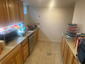 A kitchen with wooden cabinets, a microwave, a sink, and a countertop with various items. - Private Boulder Guest Suite with Kitchen, Near Trails & Downtown (Boulder)