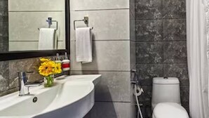 Un baño con lavamanos, espejo y retrete blancos.