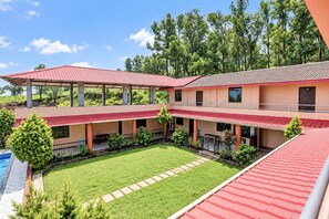 A multi-story building with a swimming pool, covered outdoor seating, and a well-maintained lawn.