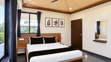 A modern bedroom with a bed, a ceiling fan, a window with curtains, and a wall-mounted mirror.