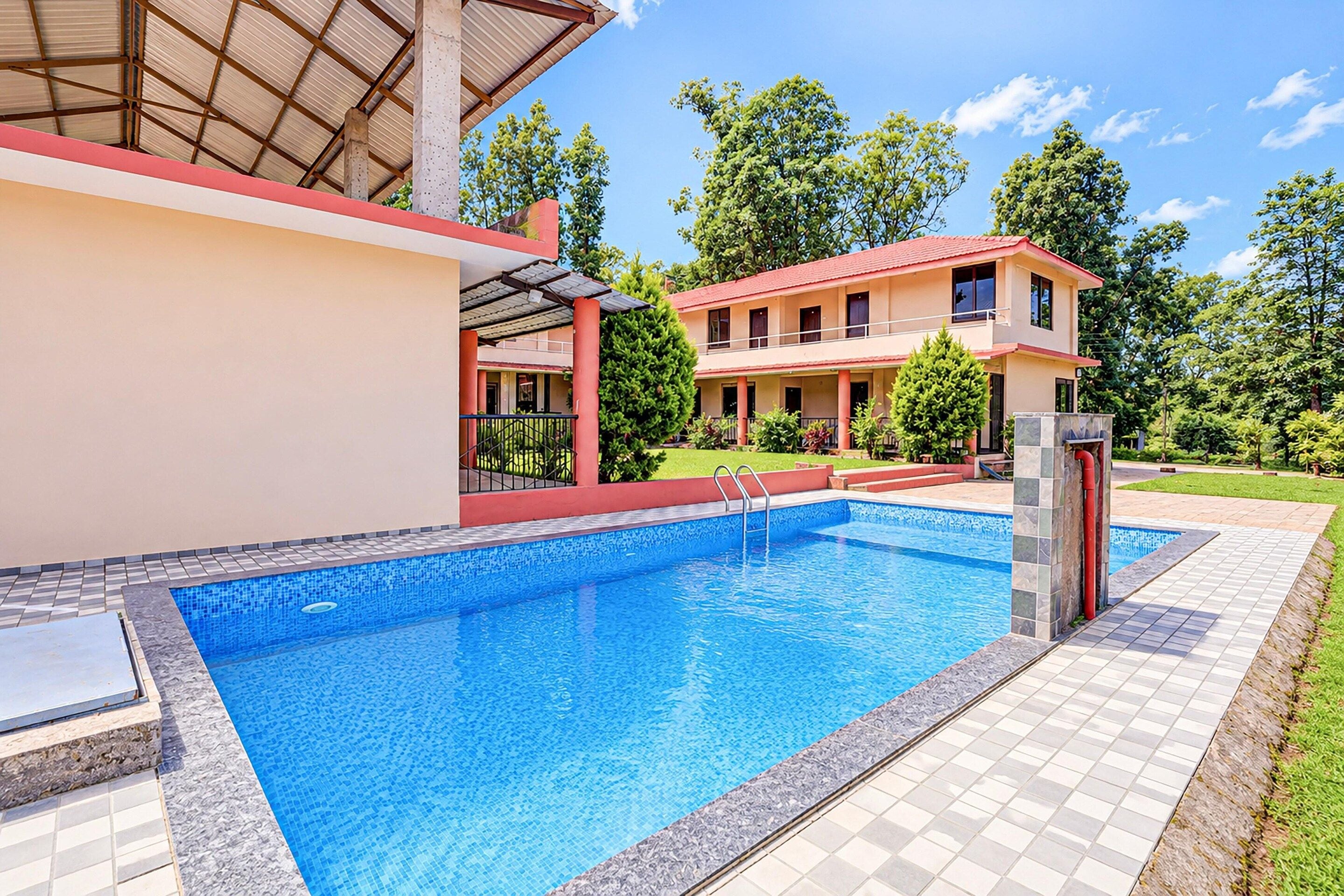 A modern two-story building with a swimming pool, surrounded by greenery.