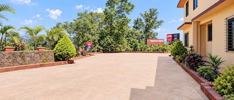 Un patio empedrado con un muro de piedra, rodeado de abundante follaje y árboles.