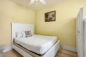 Un dormitorio con cama, un cuadro en la pared y un armario blanco.