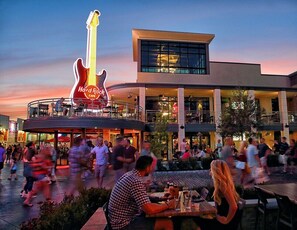 Een Hard Rock Cafe met een groot gitaarbordes, terras en een modern gebouw met grote ramen.