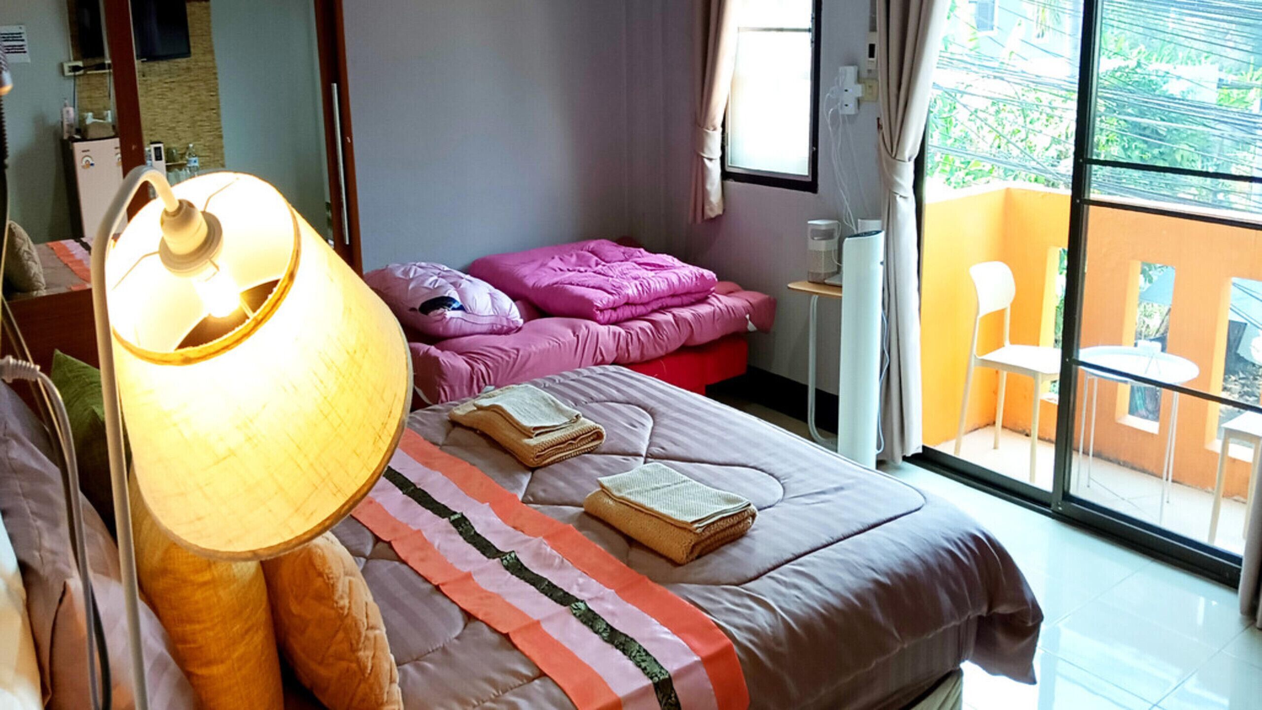Un dormitorio con cama, lámpara de noche y vistas al balcón exterior.