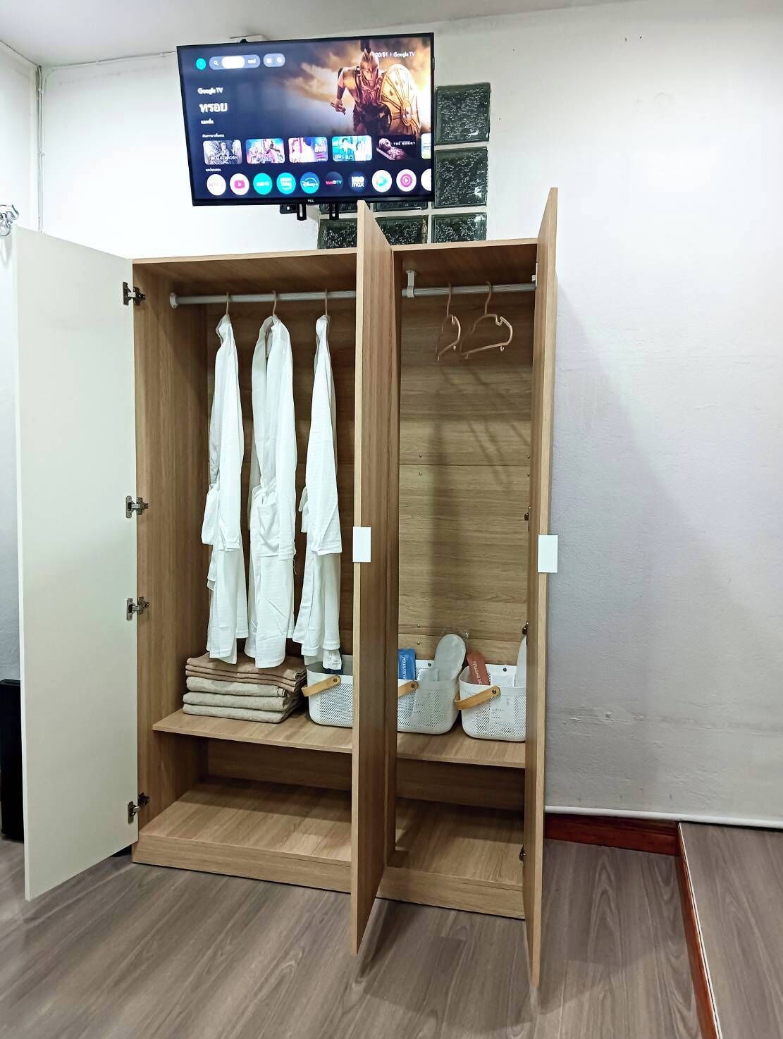 A wooden wardrobe with a television mounted above it displaying a Google TV interface.