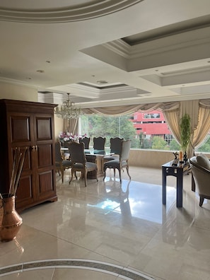 A spacious room with a dining area, a large cabinet, and a view of a red building.
