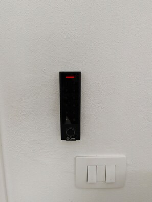 Ein an der Wand montiertes elektronisches Gerät mit einer numerischen Tastatur und dem CDVI-Logo, neben einem weißen Lichtschalter.