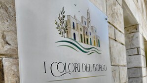 A sign with a building illustration, the name 'I Colori del Borgo', and the location 'Eleganza Mediterranea - Pulsano'. - A brand-new facility in the center of Pulsano (TA), opening in July 2026! (Pulsano)