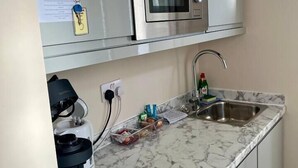 A compact kitchen with a built-in microwave, a sink, and a coffee maker.