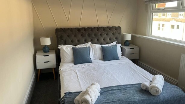 A hotel room with a large bed, two bedside tables, and a window with a view.