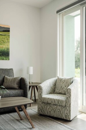 A modern living room with a sofa, armchair, coffee table, and a lamp. - New Vineyard Cottage in Niagara Wine Country | 2BR | Pet Friendly (Lincoln)