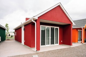 Un edificio rojo con techo blanco, un porche cubierto y una puerta corrediza de vidrio.