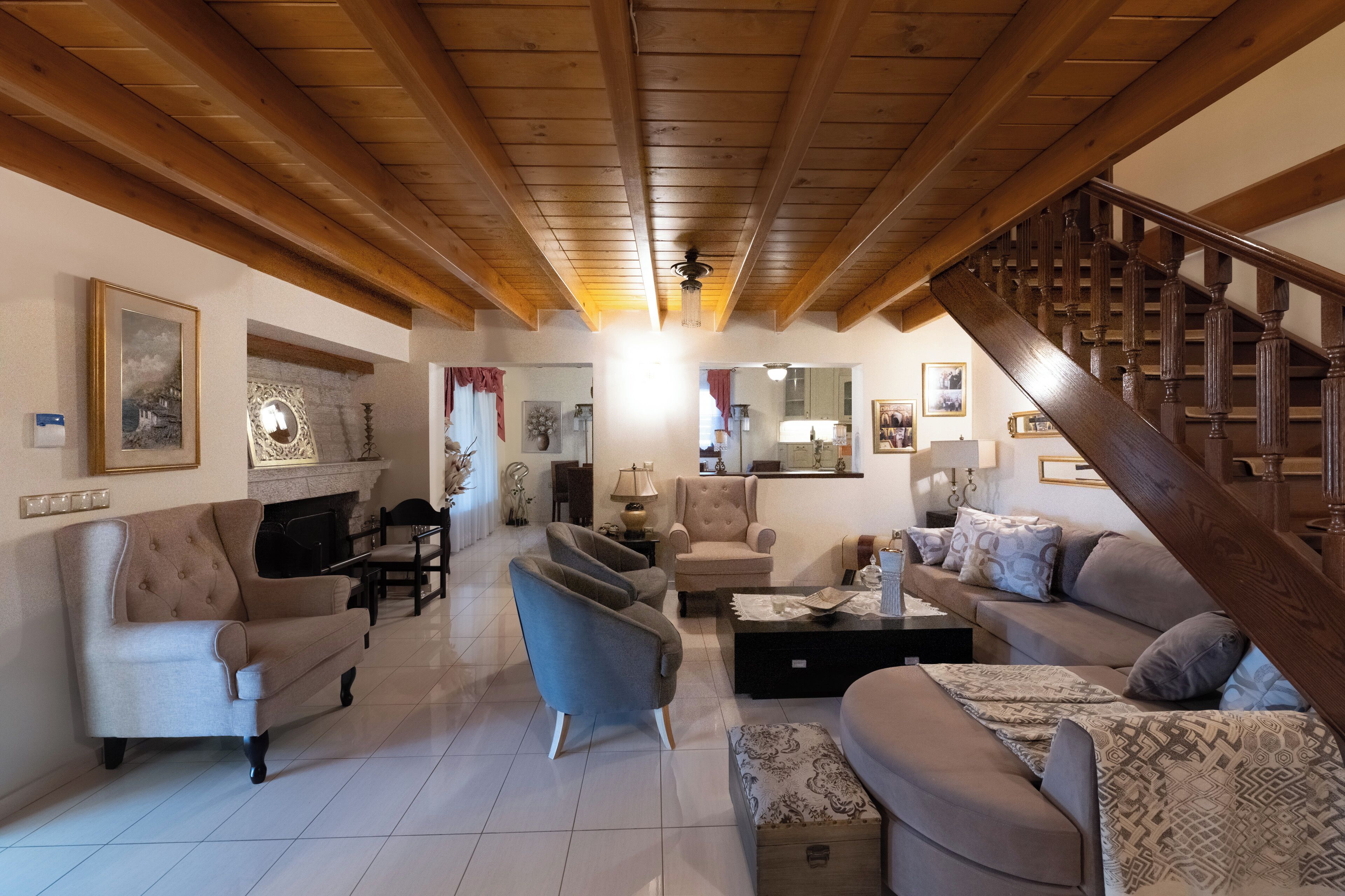 A spacious living room with a high wooden ceiling, a staircase, and a dining area.
