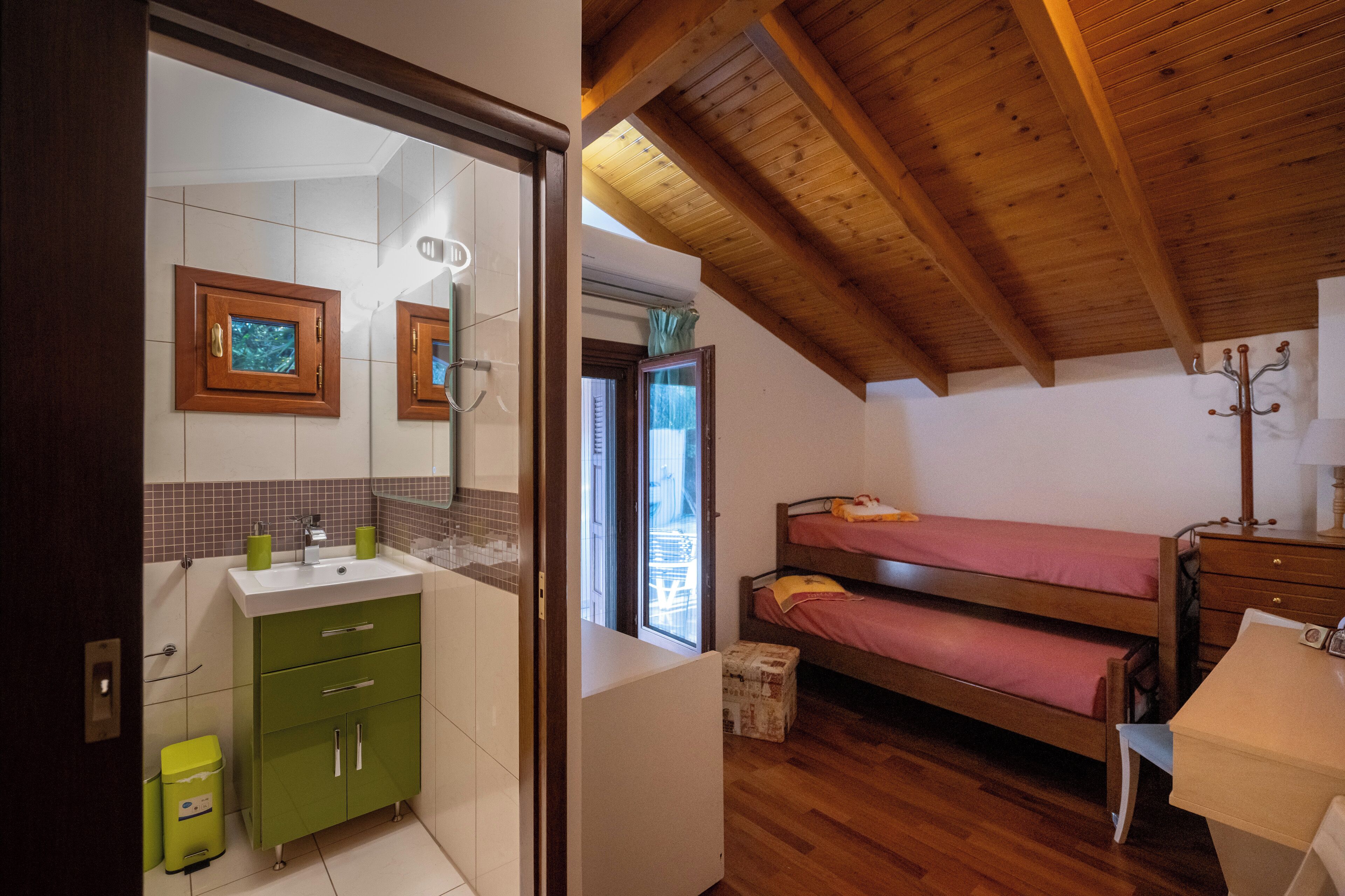 A compact bedroom with a bunk bed, a small bedside table, and a window.