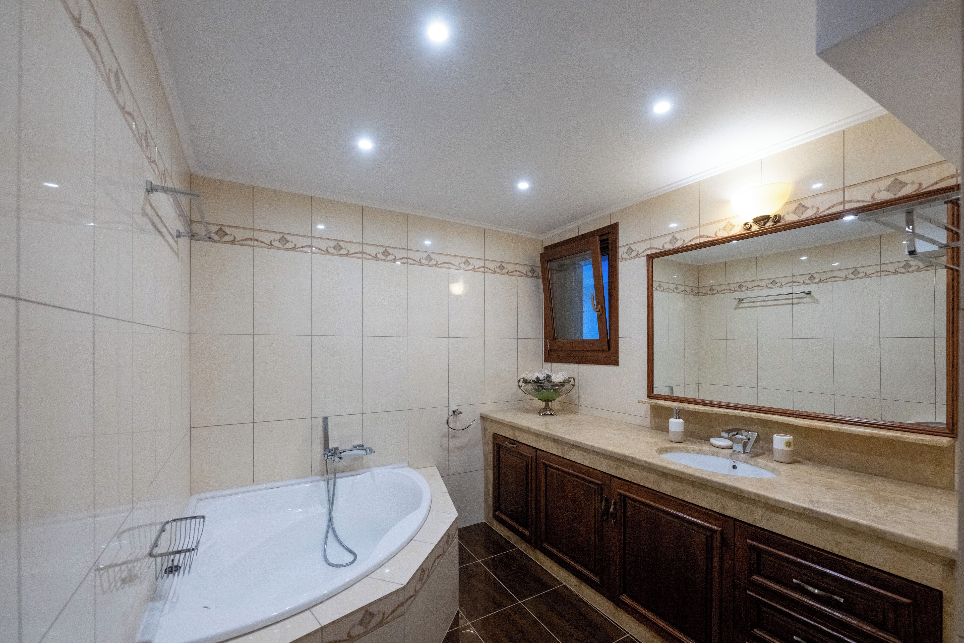 Un baño con bañera, lavamanos, espejo y tocador con armarios.