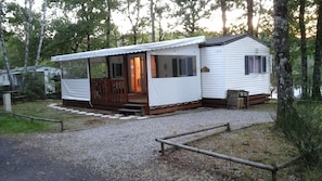 Ein Wohnmobil mit Veranda, einer kleinen Terrasse und einem Schotterweg.
