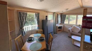 A compact RV interior with a dining area, kitchenette, and a seating area.