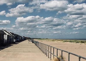 A boardwalk with beach huts and a sandy beach. - Luxury Caravan Situated on Holistic Wellbeing Site (Mablethorpe)